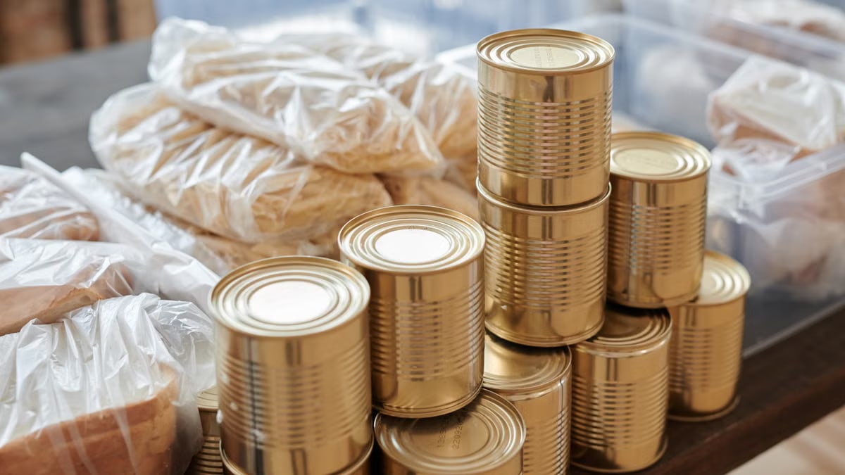 A stack of canned goods and packaged foods on a table, perfect for donation drives.